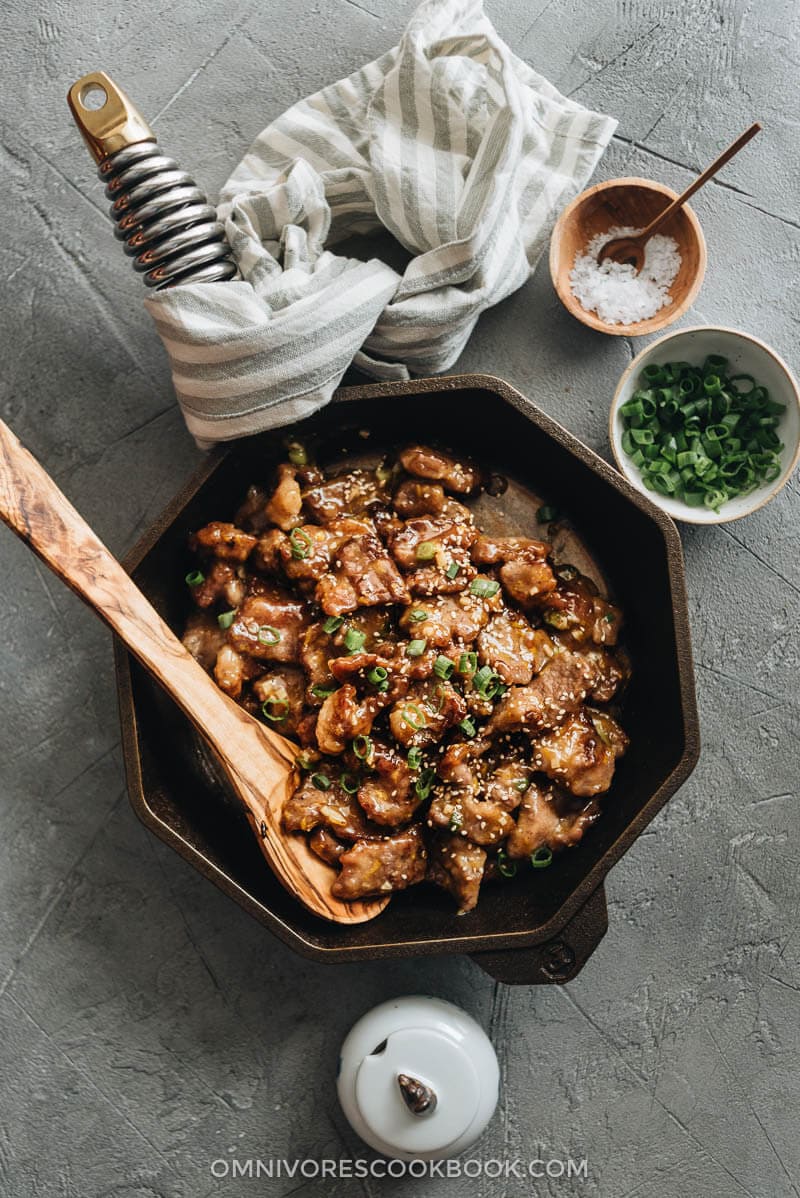 Orange beef in a cast iron skillet with green onion and salt on the side