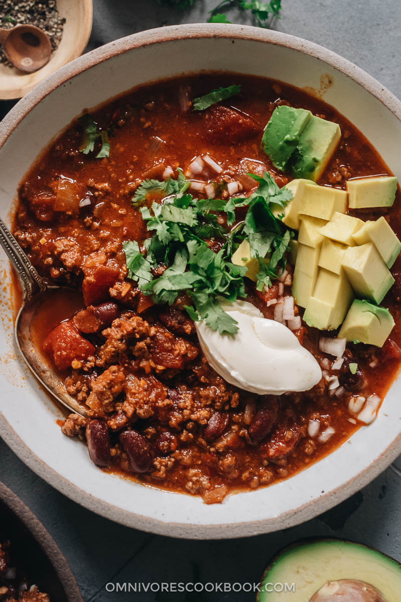 Chili served with cream cheese, cilantro, and avocado