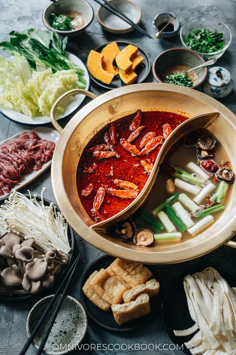 Hot pot with Sichuan spicy soup and non-spicy soup and spread of ingredients close up