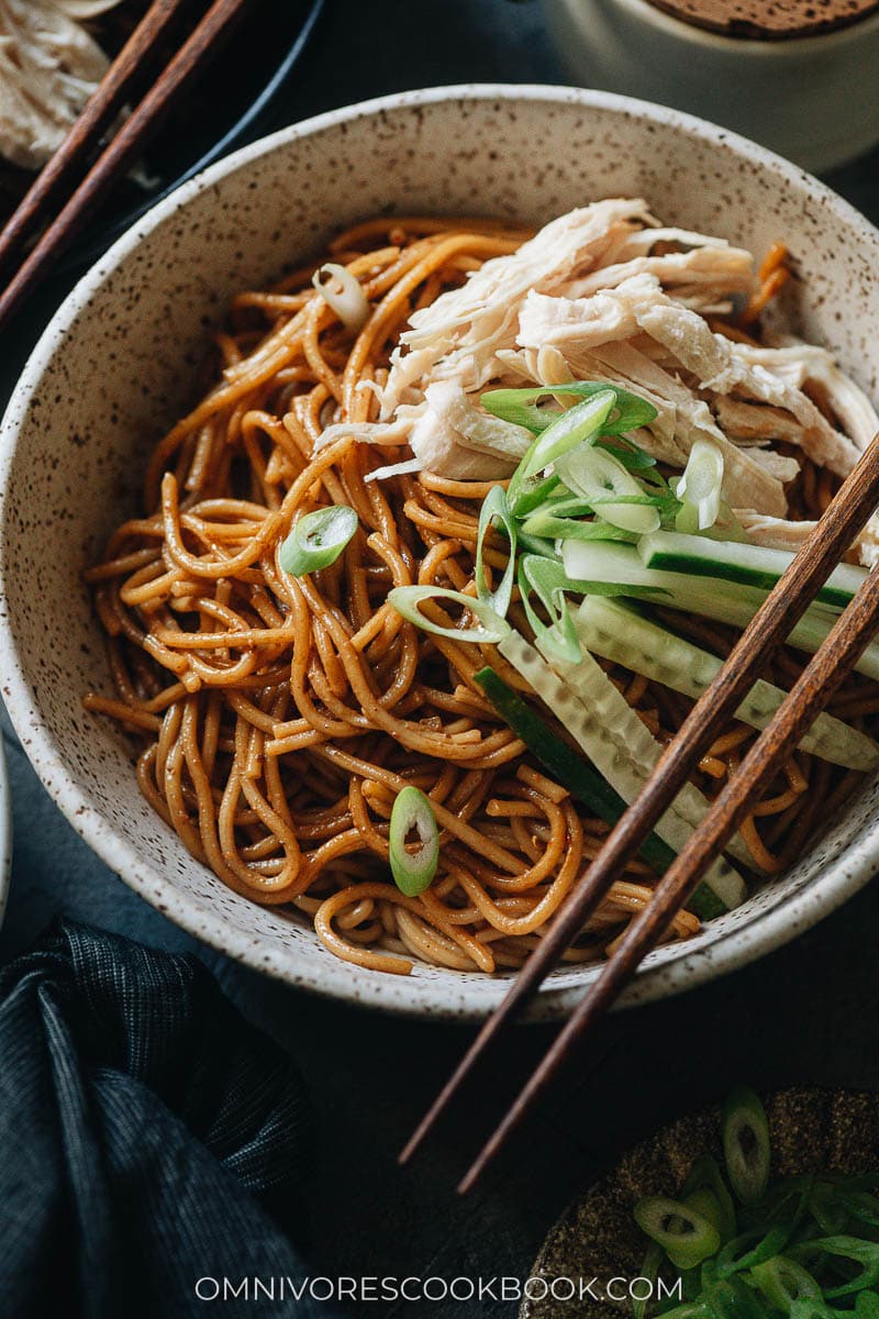 Chinese chicken noodle salad garnished with cucumber with chili oil on the side